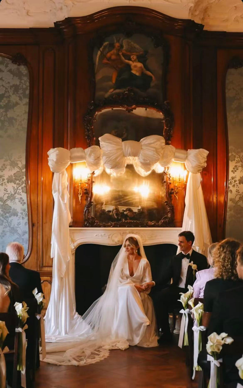 Wedding ceremony in a grand room with a large mirror and decorative lights.